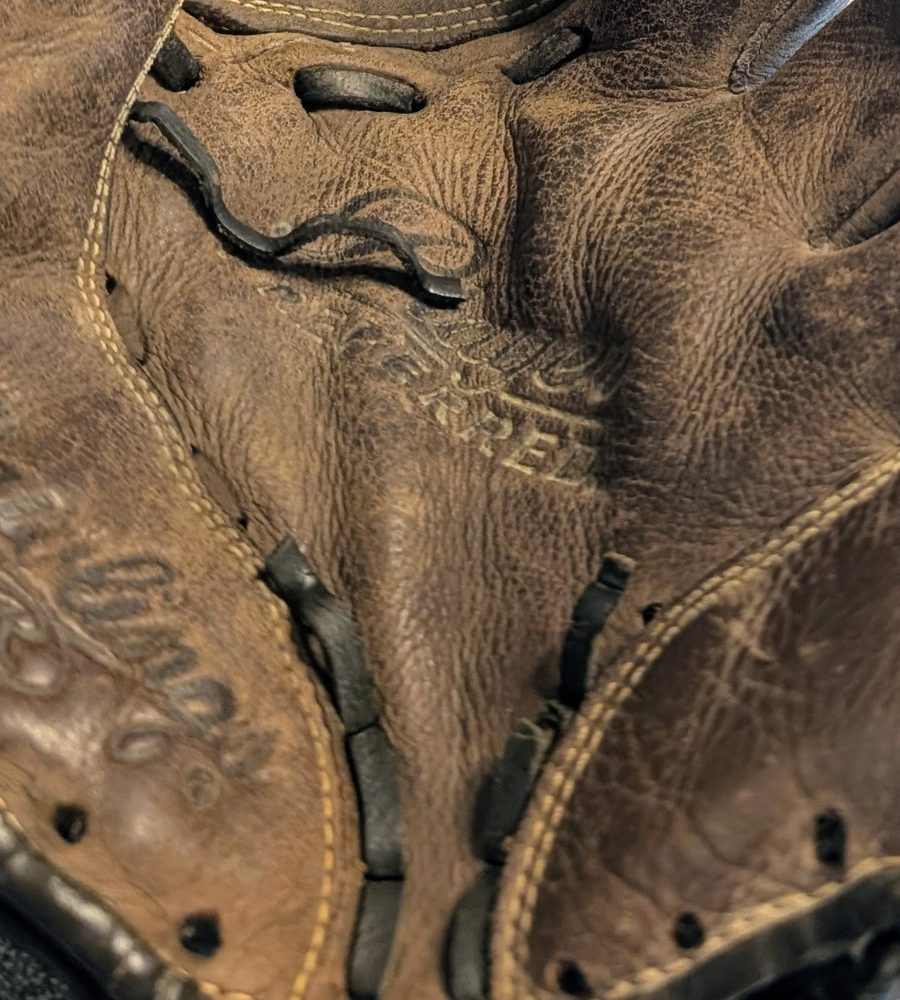 Worn baseball glove with frayed, broken black lace before repair
